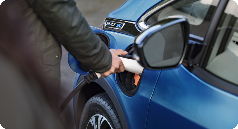 Person plugging electric vehicle charger into vehicle charge port.