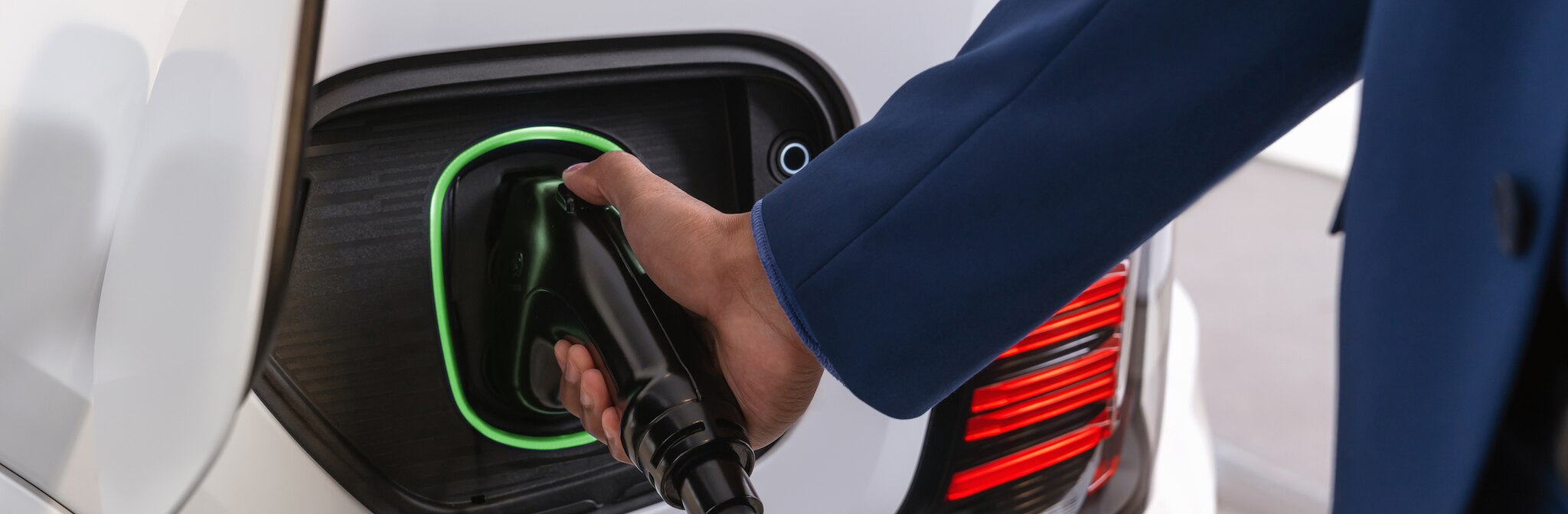Someone's hand plugging charger into electric vehicle